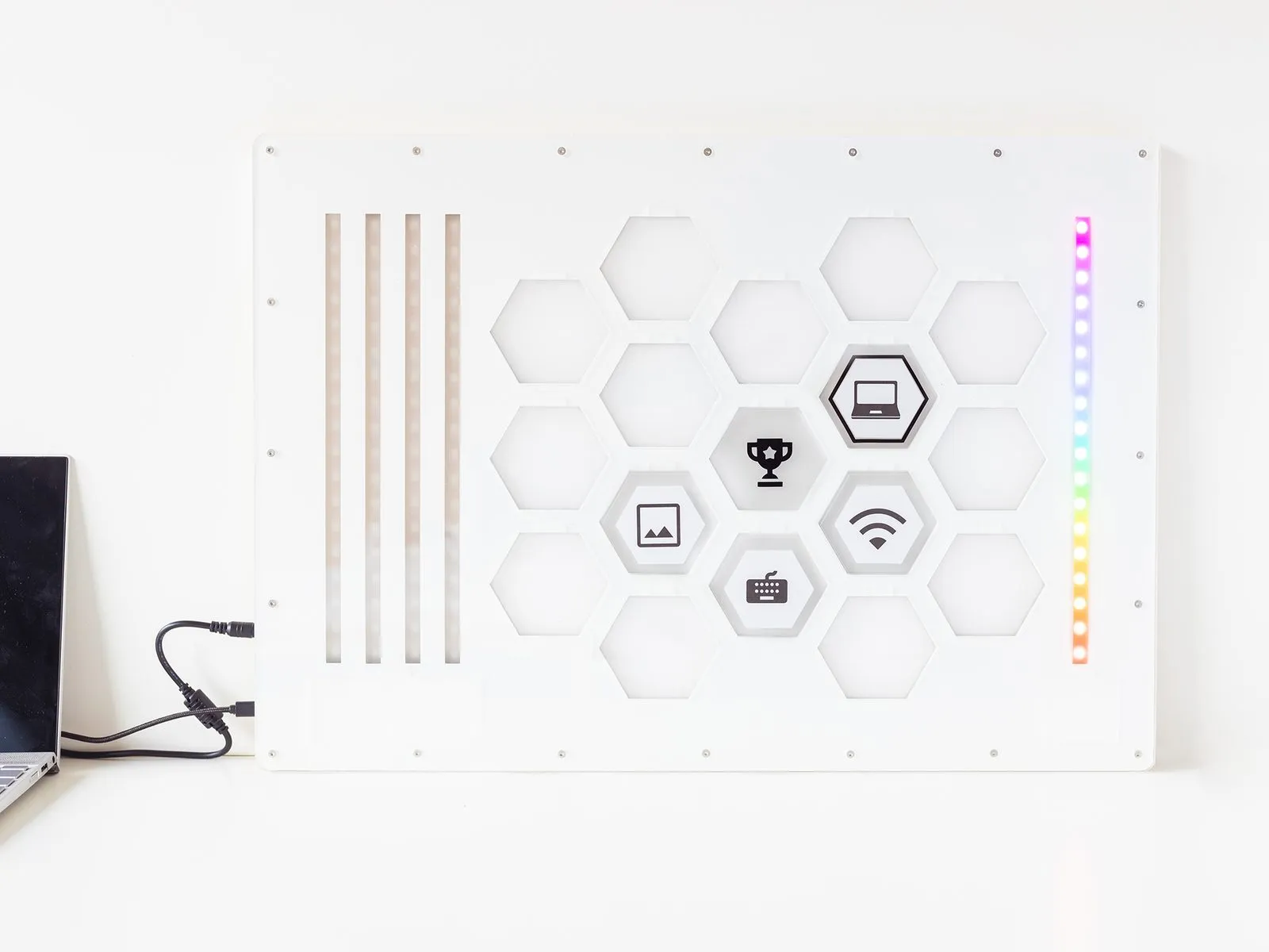 Het volledige Hiveboard: een wit paneel met zeshoekige vakken, iconen en een gekleurde ledstrip langs de rand.