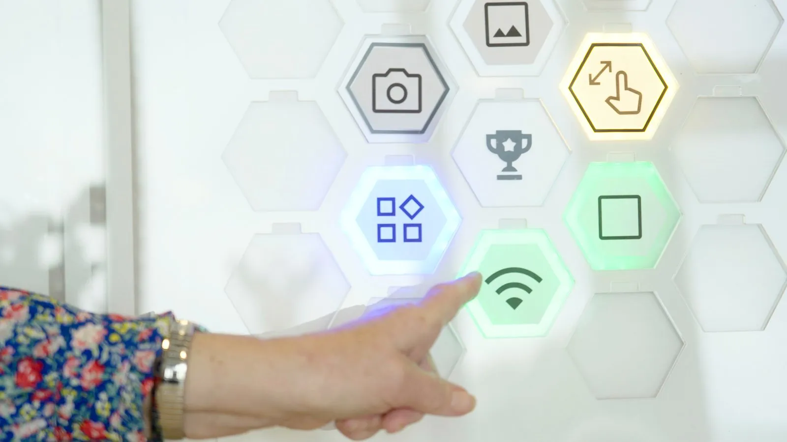 Een vinger drukt op een groen oplichtende zeshoek met een wifi-icoon.
