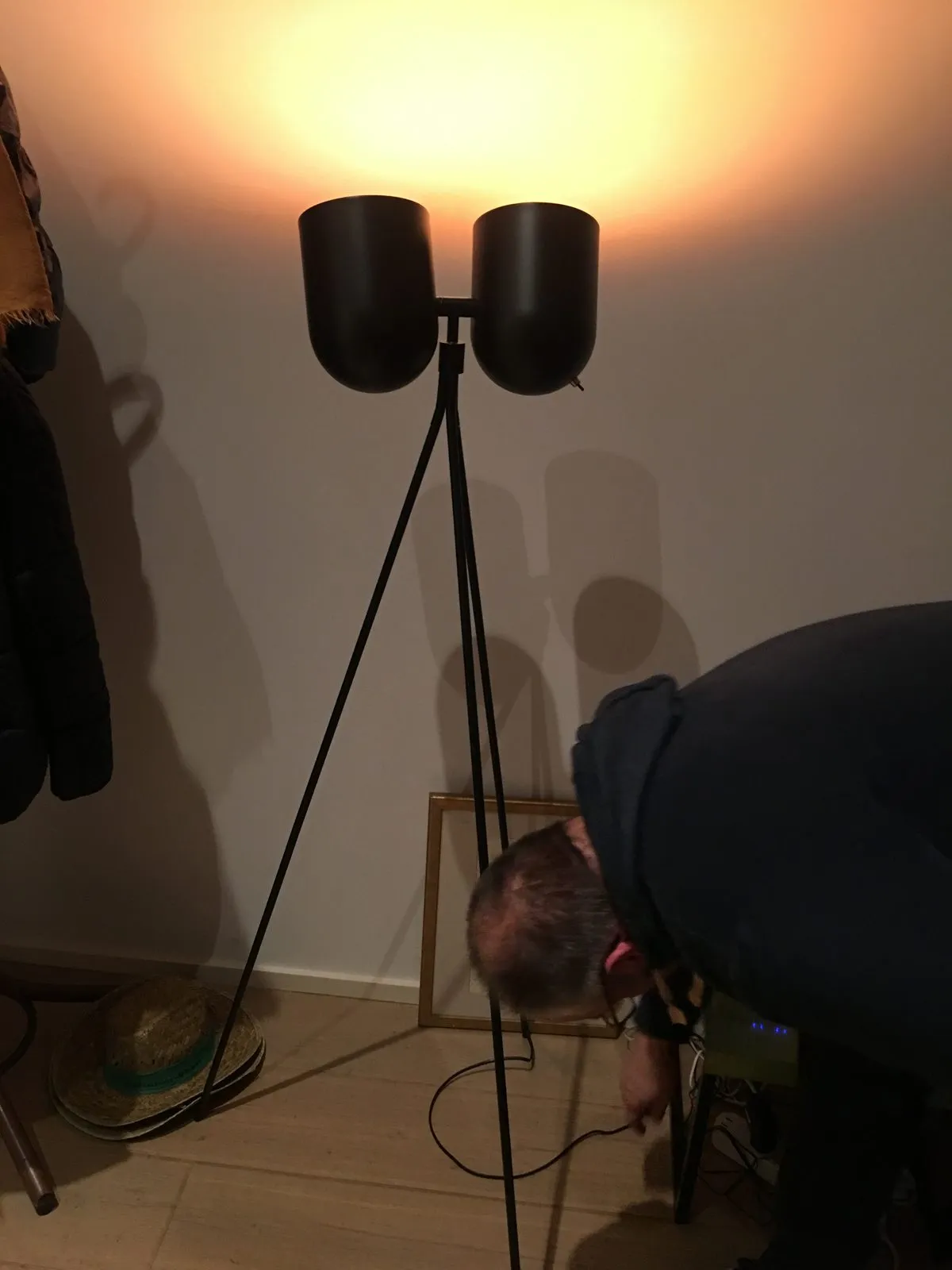 Een designlamp in een woonkamer licht warm op, met de dimmer op de grond ernaast.