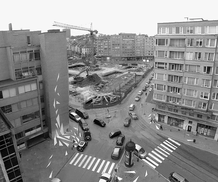 Overzicht in zwart-wit van het kruispunt: het zebrapad op straat en de scherven die het gebouw op klimmen.