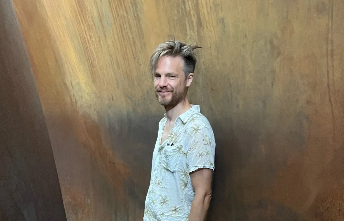 Thomas Laureyssens voor een roestbruine stalen wand.