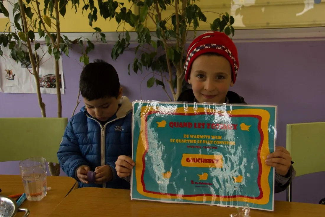 Het certificaat van de warmste buurt, in oranje en turkoois, met twee mussen erop.