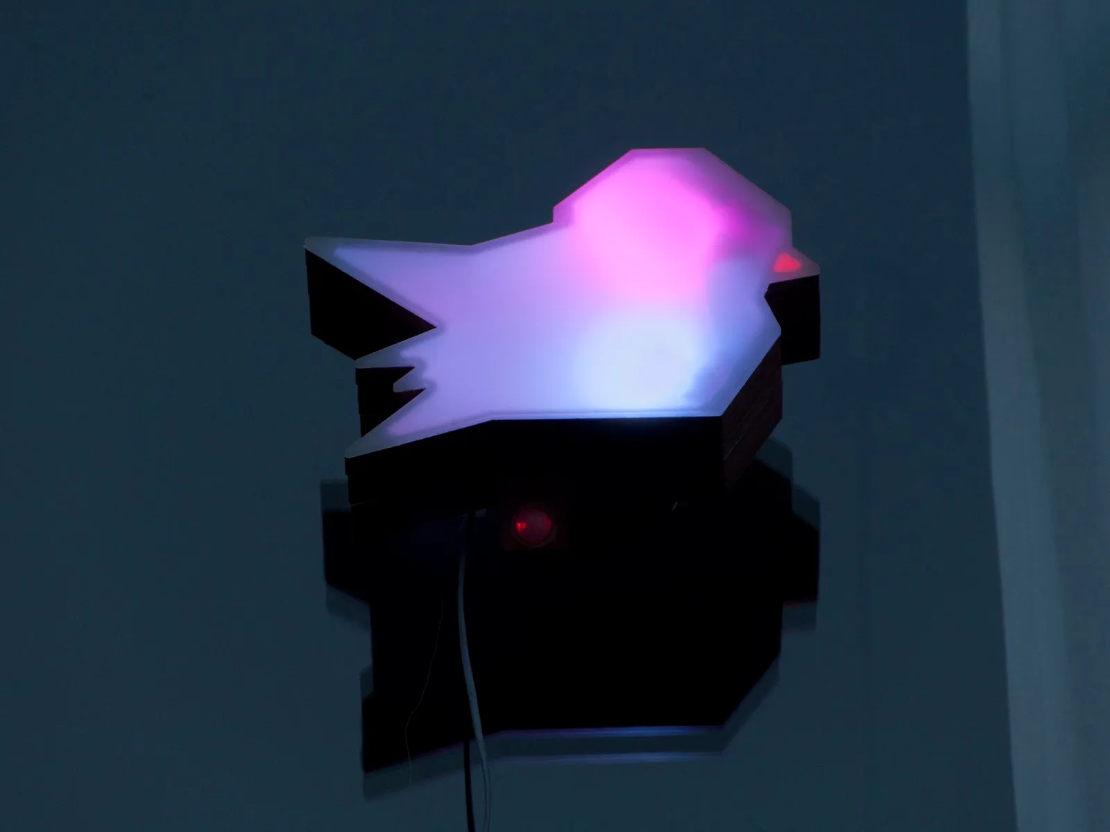 Een uitgesneden mus van plexi, van binnenuit verlicht in roze en blauw.
